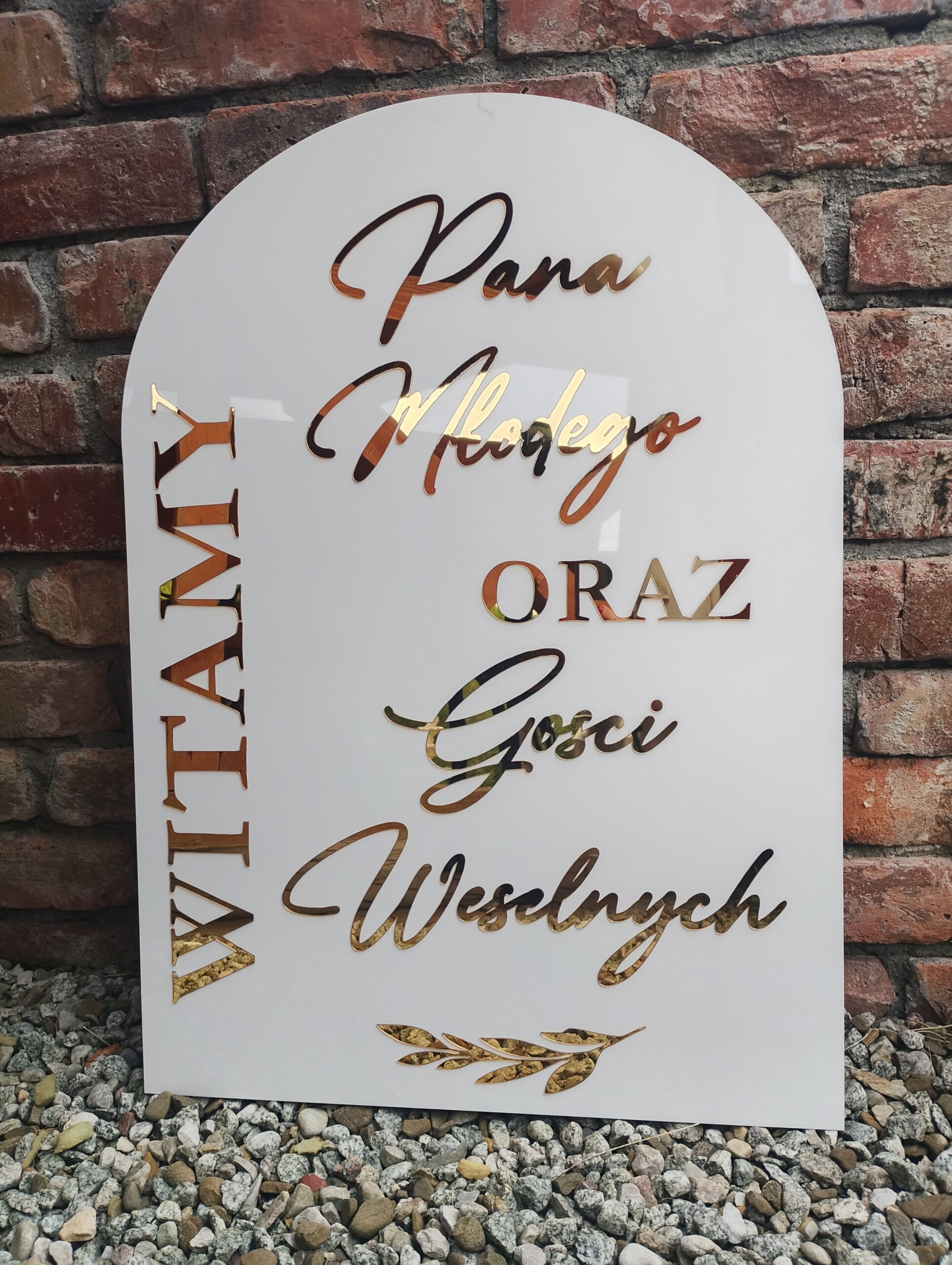 Biała, łukowata tablica powitalna z napisem